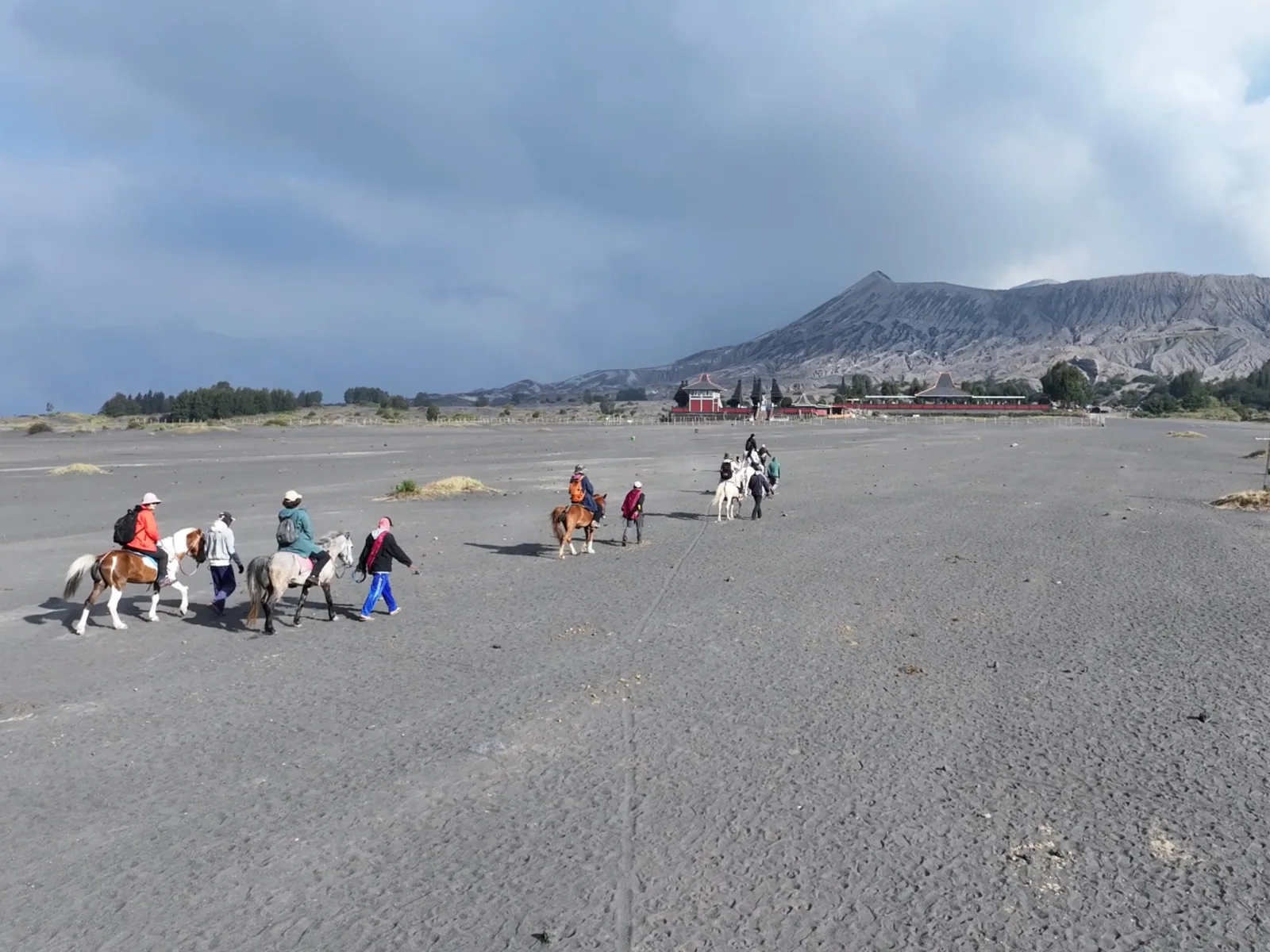 Travellers riding horses across the Mount Bromo Sea of Sand
