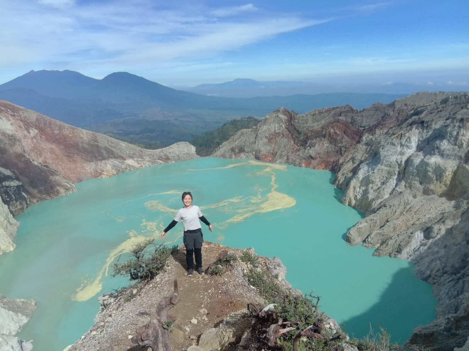 Traveller with the fully visible turquoise Ijen Crater panorama