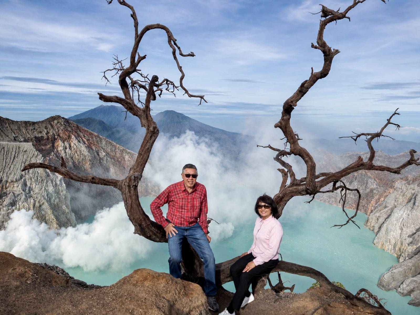 Two travellers overlooking the clear turquoise Ijen Crater