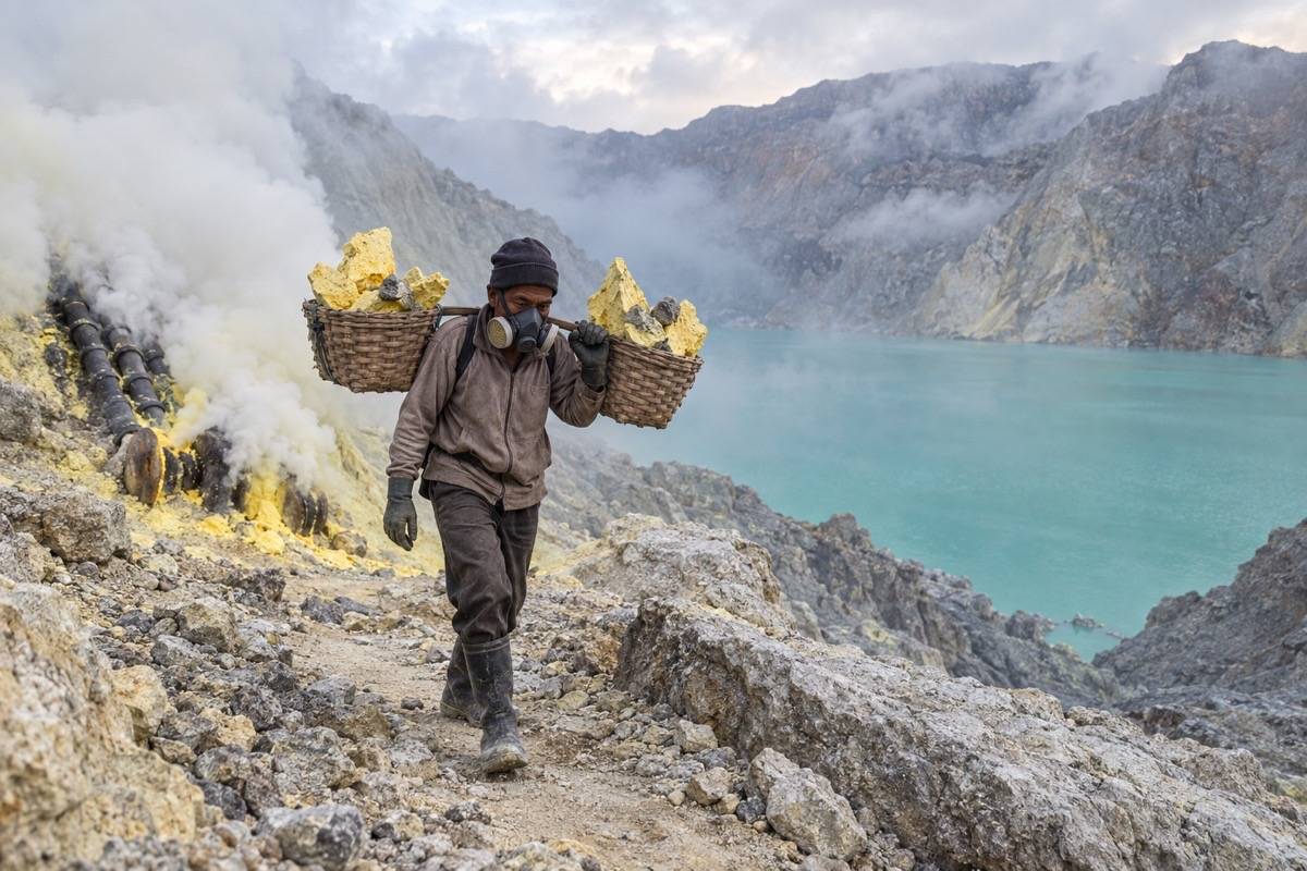 Sulfur miner carrying baskets beside the Ijen Crater lake
