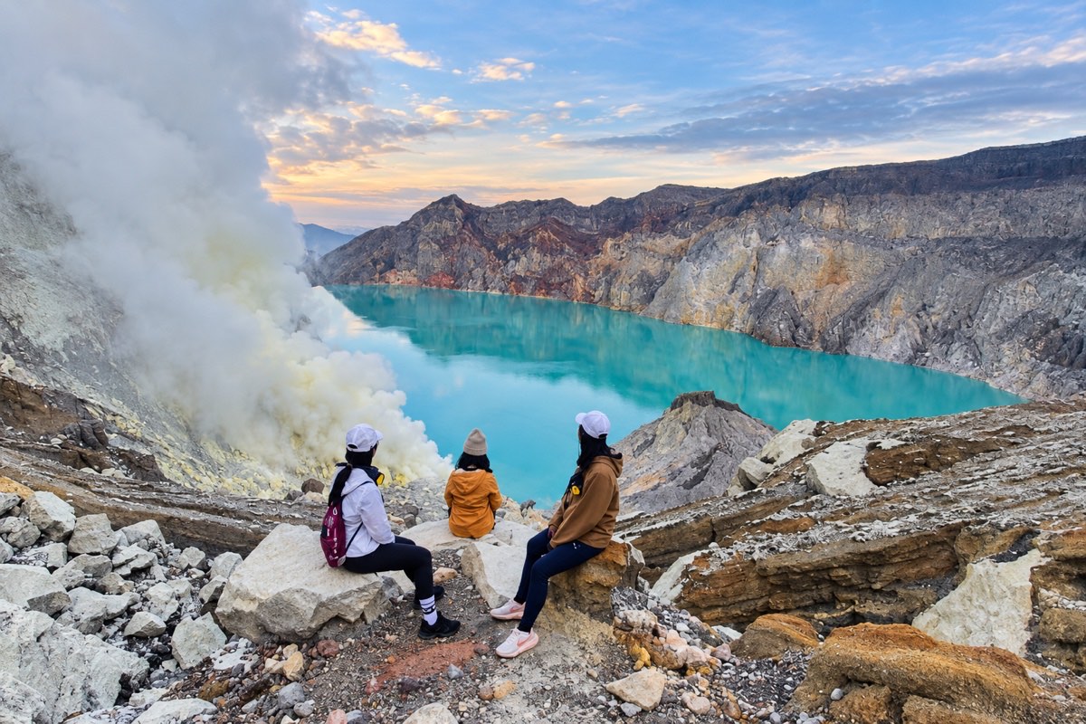 Three travellers overlooking Ijen Crater Lake at sunrise