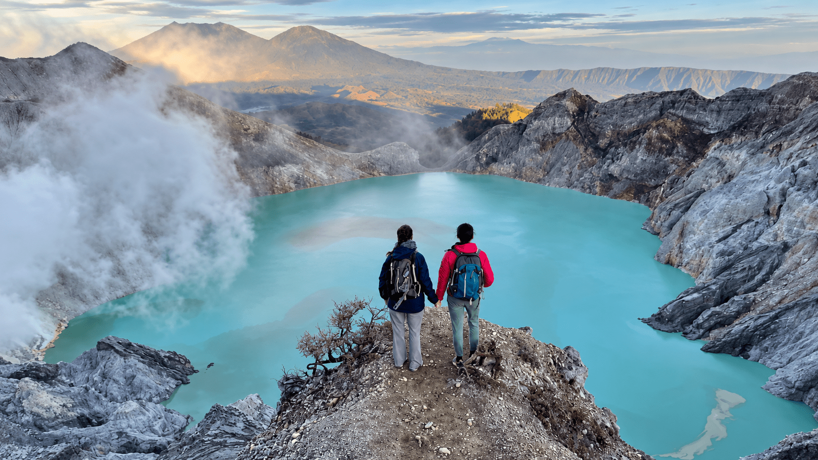 Two travellers overlooking Ijen Crater at sunrise